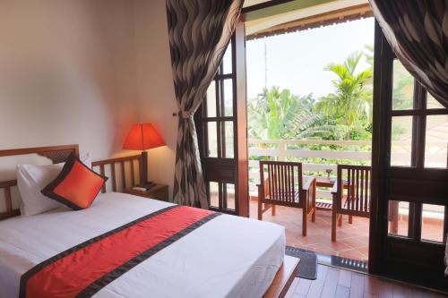 a bedroom with a bed and a sliding glass door at Windbell Villa Hoi An in Hoi An