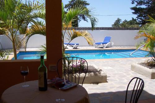 a table with a bottle of wine and two chairs next to a pool at Apartamentos Villa María in Los Llanos de Aridane