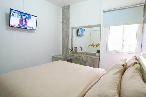 a bedroom with a bed and a tv on the wall at De Green Inn @aeropolis in Tangerang