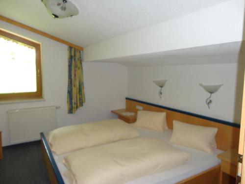 a bedroom with a bed with white sheets and a window at Ferienhaus Regina in Tux