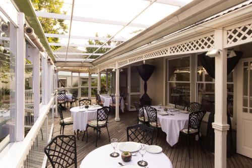 a restaurant with white tables and chairs on a porch at Quarry Lake Inn in East London