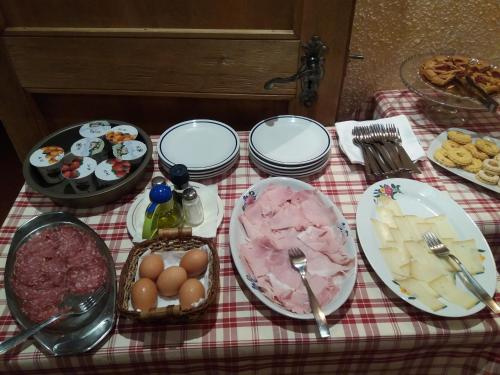 a table with plates of food on a red checked table cloth at Hotel Ottoz Meublé in Courmayeur