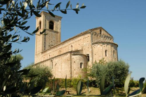 an old stone building with a clock tower on it at La Stanza Di Alice in Ponzano di Fermo