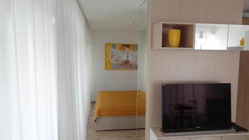 a living room with a television and a bed at Preila Holiday in Preila