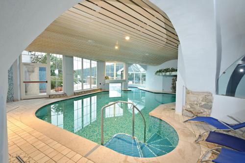 a swimming pool in a house with a large ceiling at Albergo Cavallino Bianco in Rumo