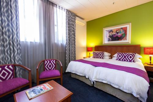 a hotel room with a bed and a table and chairs at Cape Town Lodge Hotel in Cape Town
