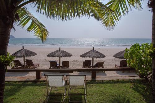 a row of chairs and umbrellas on a beach at Amata Resort & Spa, Ngapali Beach in Ngapali
