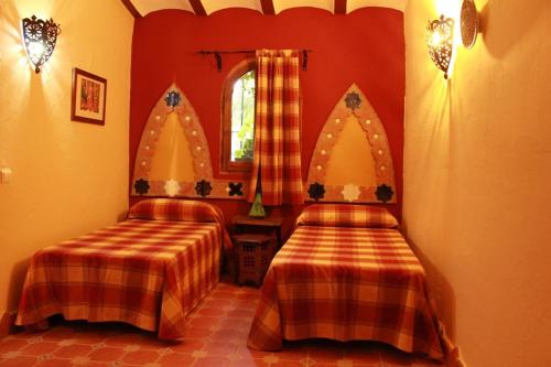 two beds in a room with red walls at Casas Cueva Cazorla in Hinojares