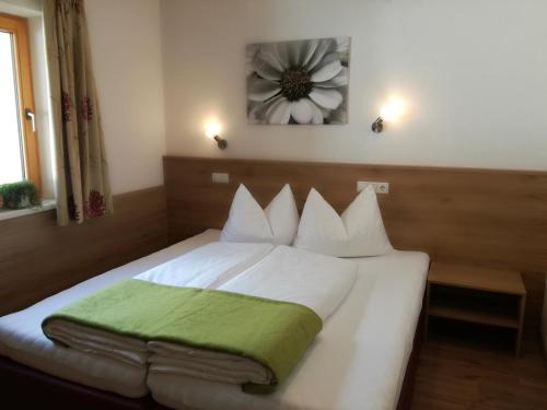 a bedroom with a white bed with a green blanket on it at Apart Diamant in Nauders