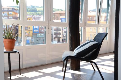 a black chair sitting in a room with windows at Andra Mari Portua in Bermeo