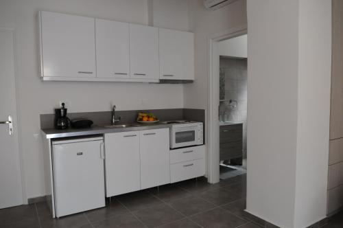 a white kitchen with a sink and a microwave at Seaside Studios in Áyioi Apóstoloi