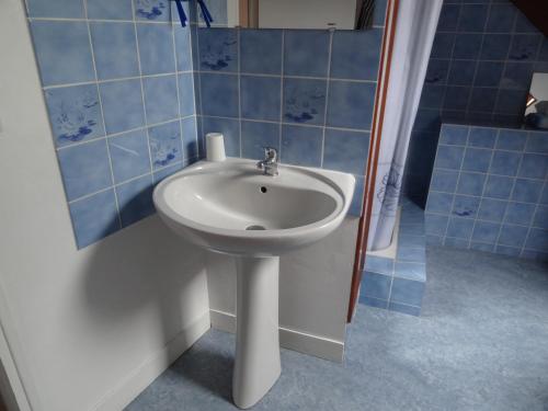 La salle de bains est pourvue d'un lavabo blanc et de carrelage bleu. dans l'établissement les Voiries chambres d'hotes, à Fleury