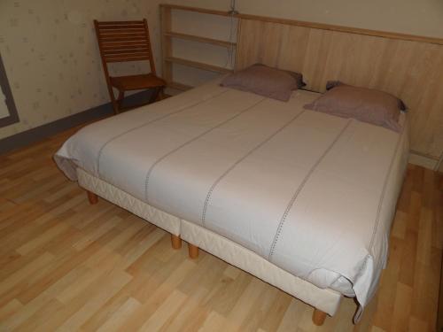 un grande letto bianco in una stanza con una sedia di les Voiries chambres d'hotes a Fleury