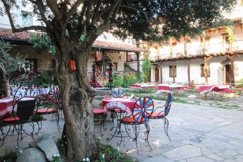 a group of tables and chairs next to a tree at Hotel Tradita in Shkodër
