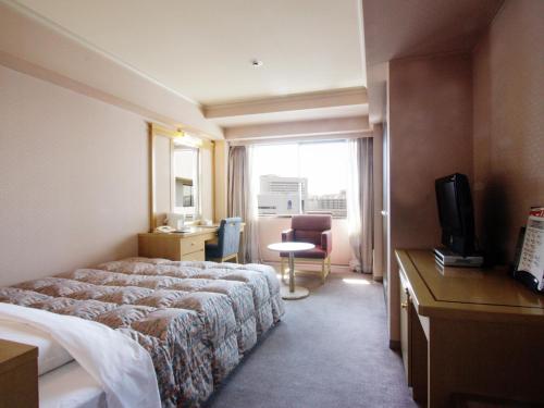 um quarto de hotel com uma cama e uma televisão em Hotel Pearl City Kobe em Kobe