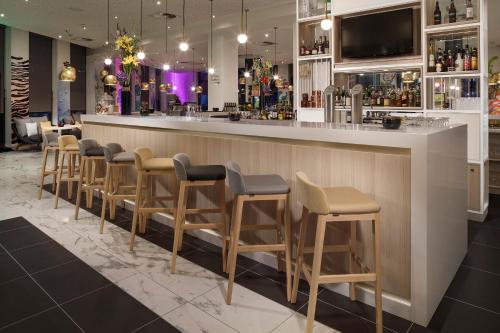 a bar with a row of stools in a restaurant at INNSiDE by Meliá Hamburg Hafen in Hamburg