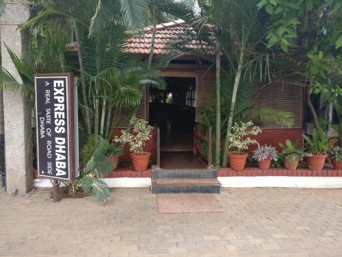 a sign in front of a building with plants at Hotel Hampi International in Hospet