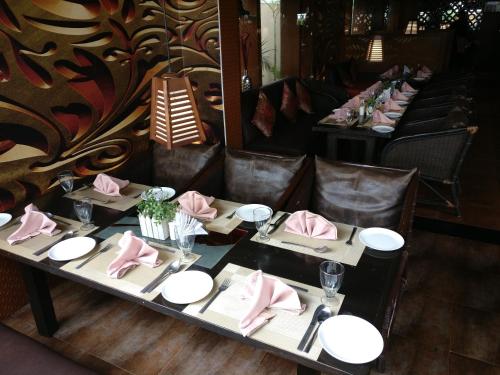 a long table with pink napkins and plates on it at Hotel Hampi International in Hospet