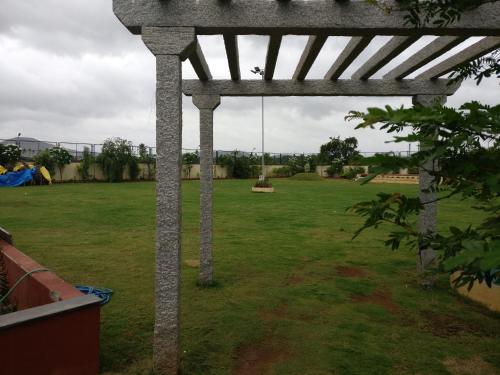 a pergola in a yard with a green field at Hotel Hampi International in Hospet