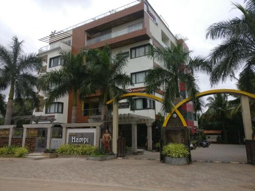 a building with palm trees in front of it at Hotel Hampi International in Hospet