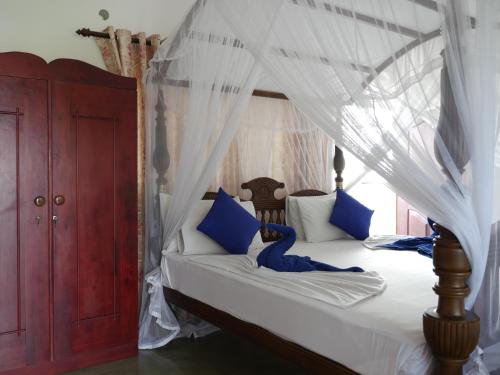 a bedroom with a canopy bed with blue pillows at Ocean View tourist guest house at Negombo beach in Negombo