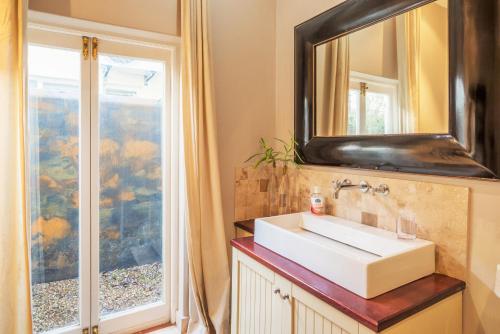 La salle de bains est pourvue d'un lavabo et d'un miroir. dans l'établissement Antrim Luxury Villa, au Cap