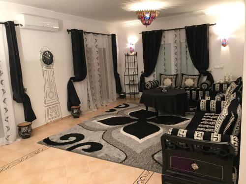 a living room with black and white furniture and a rug at Oriental Dary Al Waha Marina Saidia in Saidia 