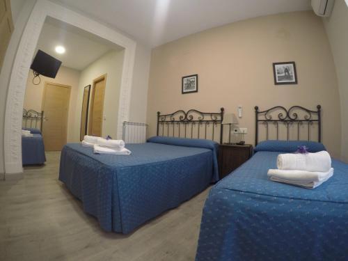 a bedroom with two beds with blue sheets and white towels at Hostal El Pilar in Madrid