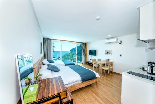a bedroom with a bed and a table and a kitchen at Jeju Aurum in Seogwipo