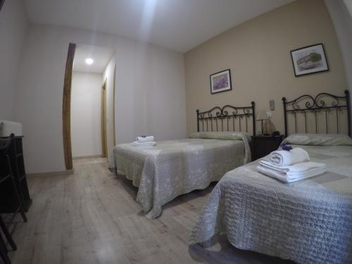 a room with two beds with white sheets and towels at Hostal El Pilar in Madrid
