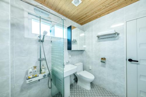 a bathroom with a toilet and a glass shower at Jeju Aurum in Seogwipo