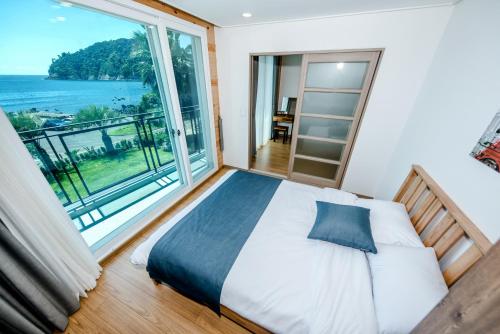 a bedroom with a bed and a large window at Jeju Aurum in Seogwipo