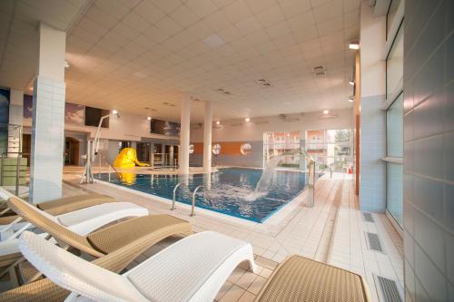 a pool with chairs and a slide in a building at Akces Medical Fit & Spa in Dźwirzyno