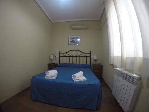 a bedroom with a blue bed with two towels on it at Hostal El Pilar in Madrid