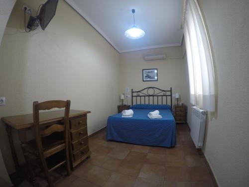 a bedroom with a blue bed and a table at Hostal El Pilar in Madrid
