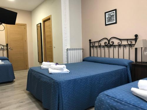 a bedroom with two beds with blue sheets and towels at Hostal El Pilar in Madrid