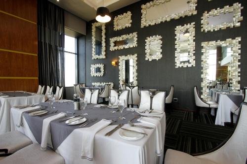 a dining room with white tables and chairs at Coastlands Umhlanga Hotel and Convention Centre in Durban