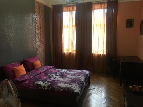 リヴィウにある1 Starodubska Apartmentのベッドルーム1室(紫のシーツと窓付きのベッド1台付)