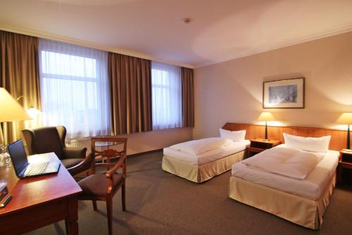 マクデブルクにあるホテル ラーツヴァーゲのベッド2台とデスクが備わるホテルルームです。