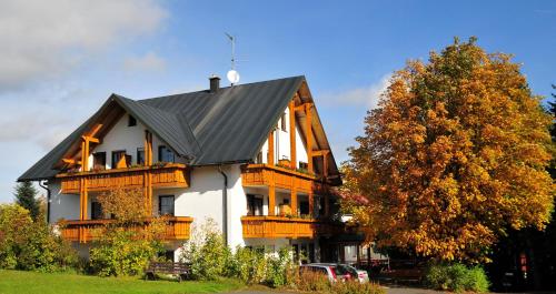 a large wooden house with a gray roof at Hotel Bergblick in Warmensteinach