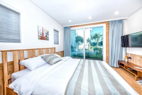 a bedroom with a large bed and a large window at Jeju Aurum in Seogwipo
