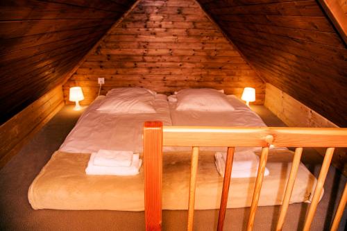 Łóżko w drewnianym pokoju na poddaszu z 2 lampami w obiekcie Urlop Przy Wydmach w mieście Międzywodzie