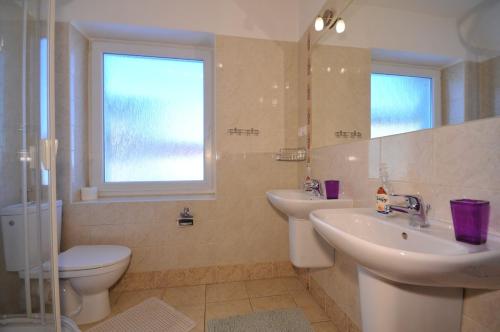 een badkamer met 2 wastafels, een toilet en een raam bij Vila Helena in Liptovský Ján