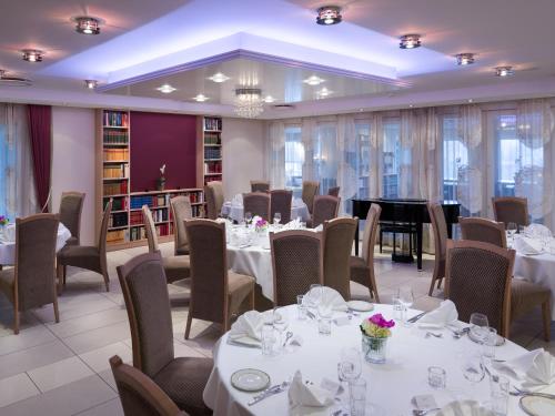 restauracja z białymi stołami i krzesłami oraz fortepianem w obiekcie Quality Hotel Olavsgaard w mieście Skjetten