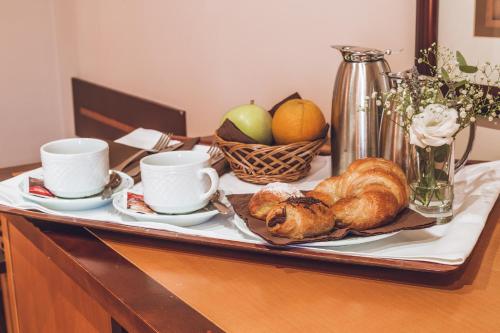a tray with bread and croissants and cups on a table at Hotel Bardo Recoletos Coco in Salamanca