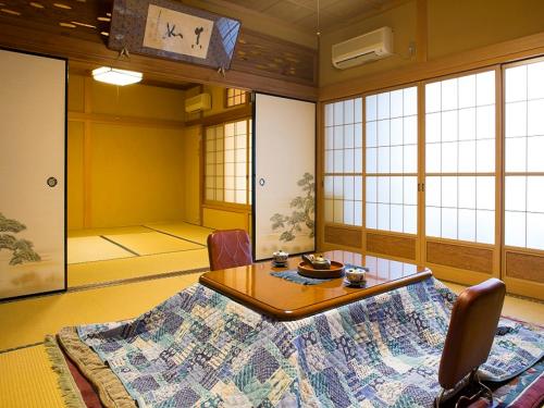 a room with a table and chairs and windows at Kanko Ryokan Kuboji in Tenkawa