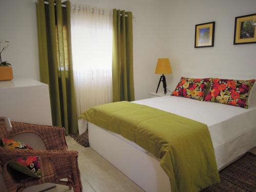 a bedroom with a bed and a chair and a window at Casa do Professor in Albergaria-a-Velha