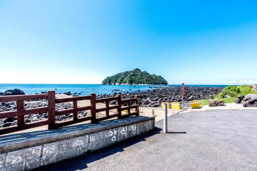 a bench on a beach with an island in the water at Jeju Aurum in Seogwipo