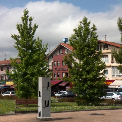 a monument in a park with two trees and a building at Hotel Aitana in Irún