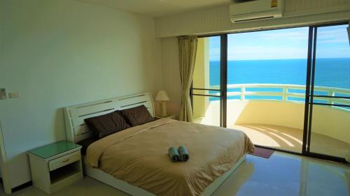 a bedroom with a bed and a balcony with the ocean at VIP Condochain Rayong 427 in Ban Phe
